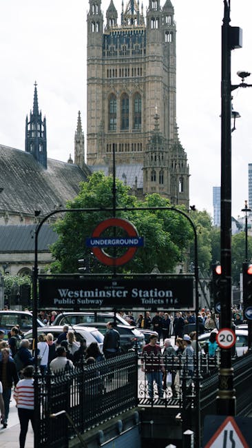 A view of Westminster Bridge spanning the River Thames in London, with the iconic Houses of Parliament and the Elizabeth Tower (Big Ben) in the background. The bridge has a classic green-painted metal